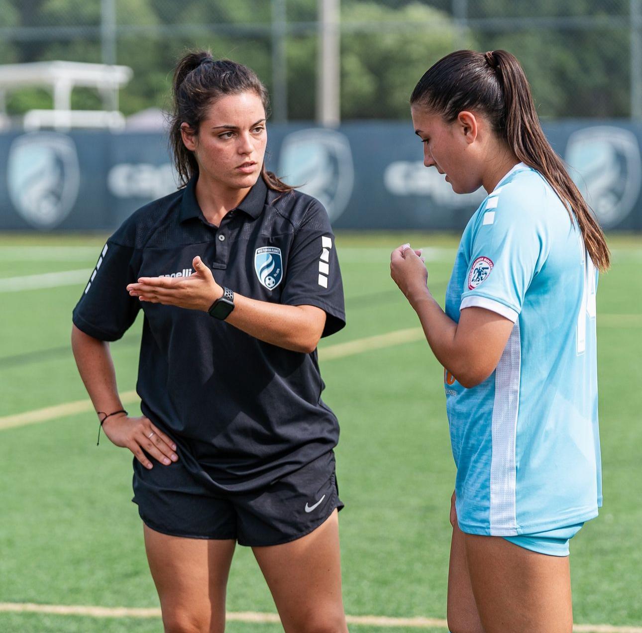 Coach giving direct technical feedback to an athlete on the touchline