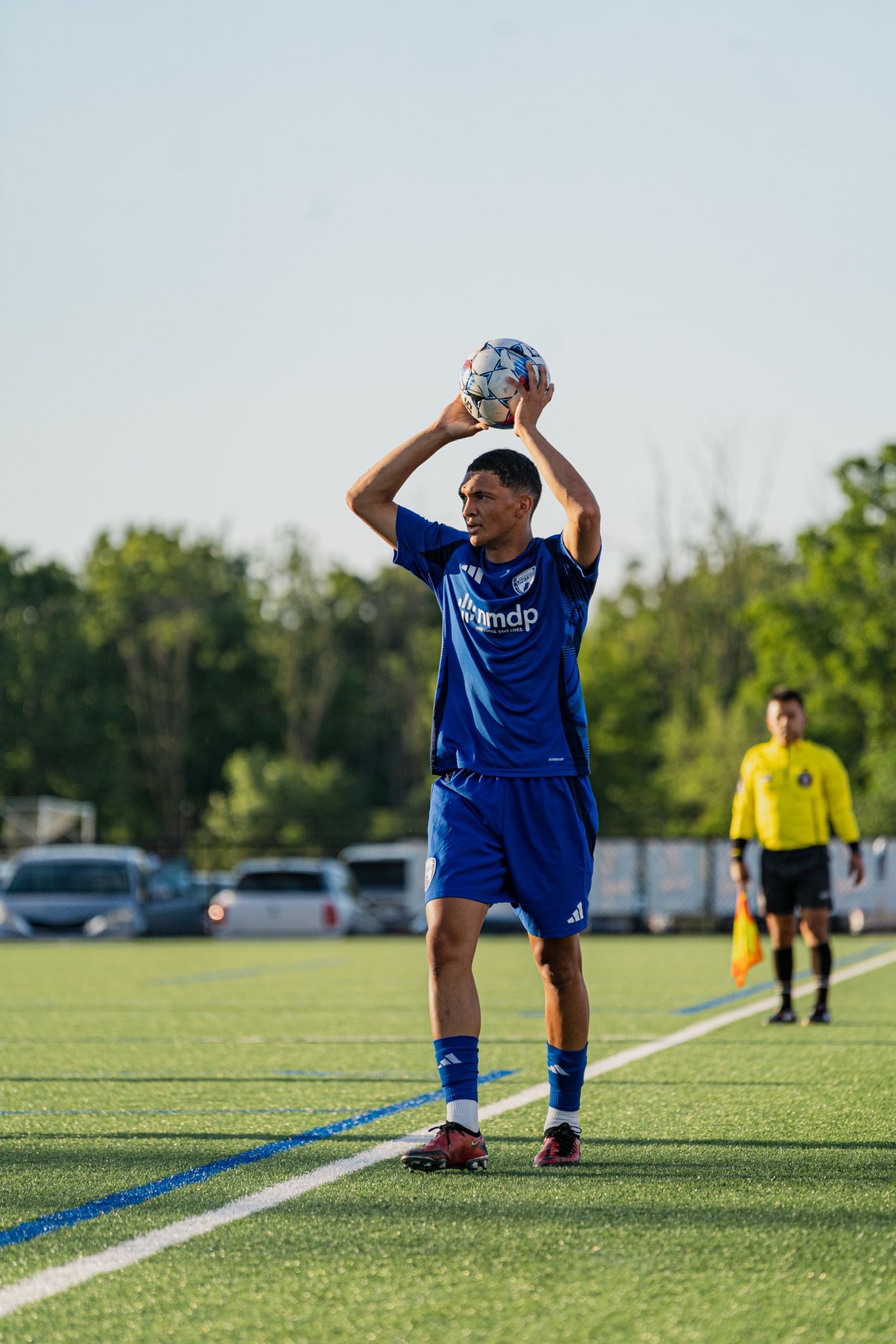 Lone athlete preparing a throw-in on a quiet field — visibility on his own